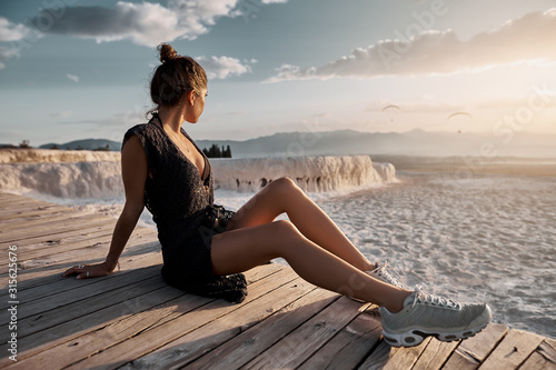 Obraz na płótnie Young sexy girl in black dress sitting at natural pool Pamukkale at sunset light. Natural travertine pools and terraces in Pamukkale, Turkey w salonie