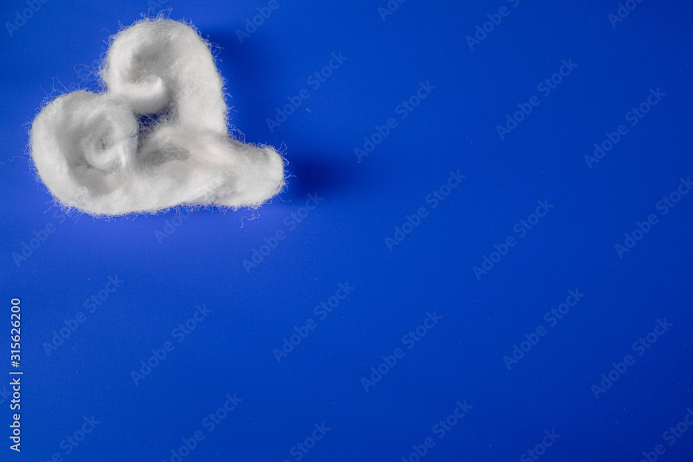 Handmade white cotton heart on blue paper background. Space copy. Flat lay. Handmade white cotton heart on blue paper background. Space copy. Flat lay.