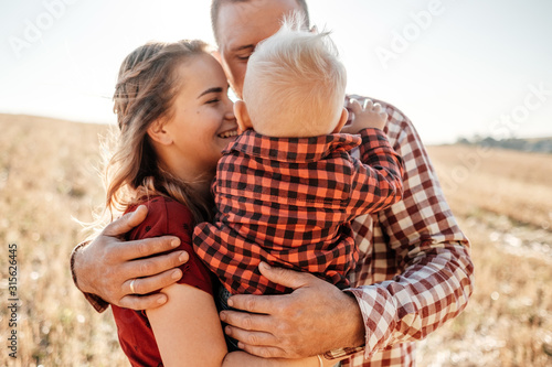 Happy Young Family Mom and Dad with Their Little Son Enjoying Summer Weekend Picnic Outside the City in the Field at Sunny Day Sunset, Vacation Time Concept