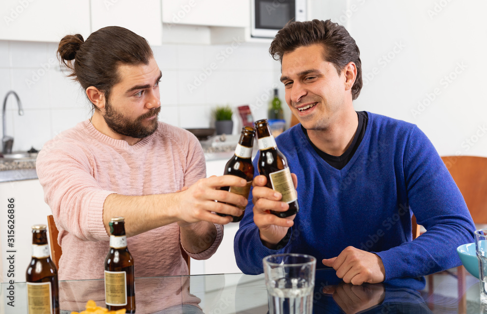 Two friends with bottles of beer celebrate happy event