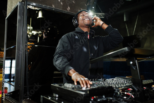 Foto African american dj play music on decks at night club.