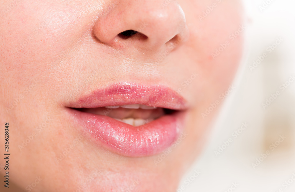 Fototapeta premium Close-up of female's lips with natural lipstick make up. macro lipgloss make-up