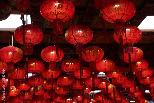 Many illuminated red Chinese lanterns with some Chinese characters on it in temple - Used across countries in Asia for celebrating Chinese New Year tradition