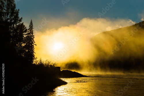 Golden fog over the siberian mountain river Small Yenisei in early summer morning. photo