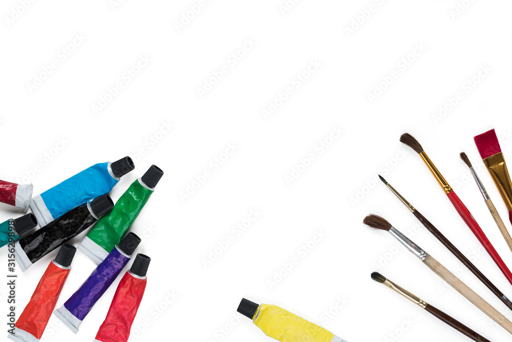 Tubes with multi-colored acrylic paints and paintbrushes isolated on white background. Creativity and hobby concept. Copy space Tubes with multi-colored acrylic paints and paintbrushes isolated on white background. Creativity and hobby concept. Copy space