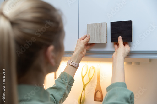 Obraz na płótnie woman choosing kitchen cabinet materials from laminate samples