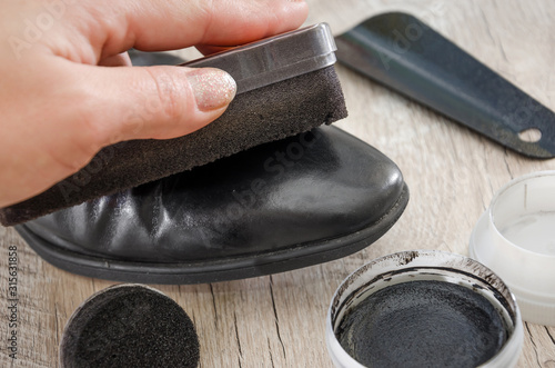 black men's shoes with accessories for care. Hand to clean a man’s shoe, close-up.