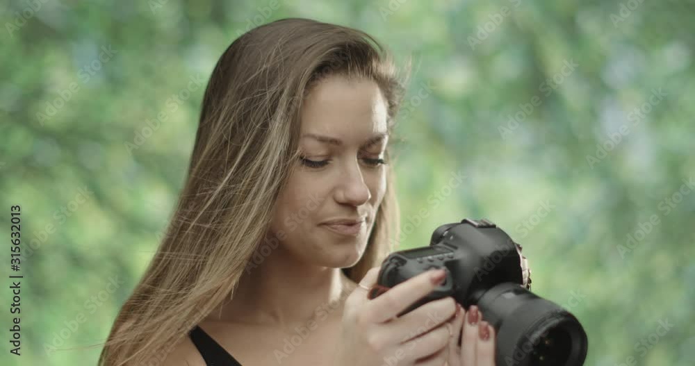 cute female photographer using her DSLR camera in nature.trees in the background. Slow motion 4K cute female photographer using her DSLR camera in nature.trees in the background. Slow motion 4K