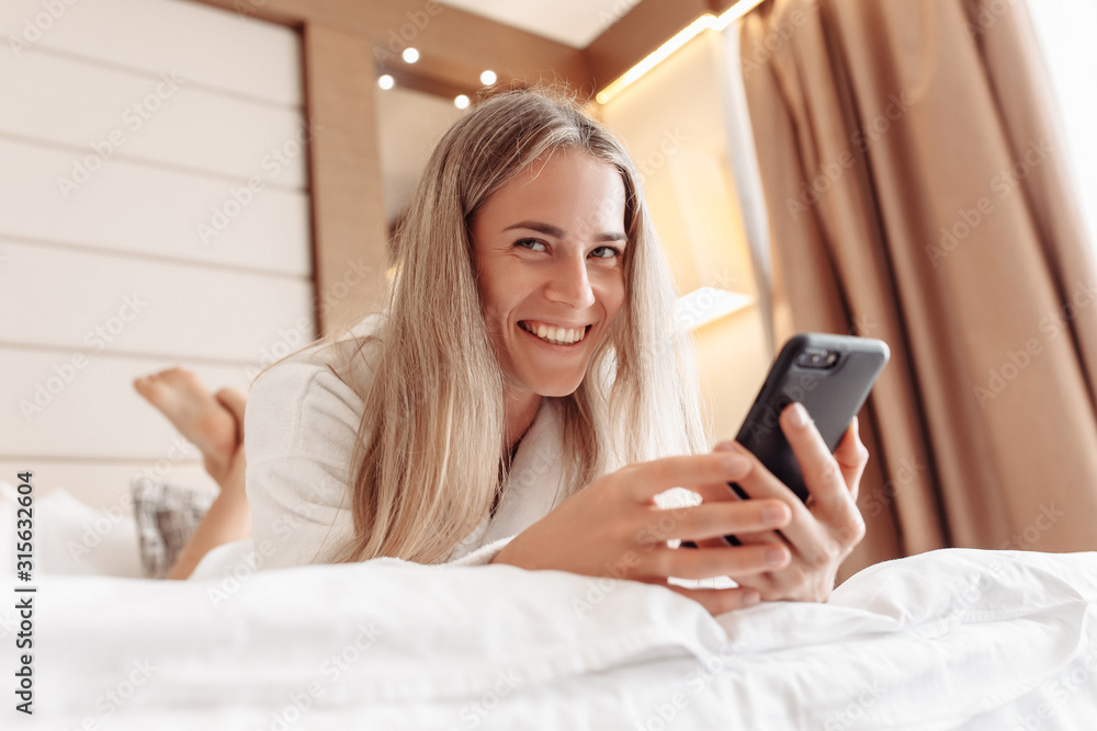 Laughing cheerful beautiful young woman watching private messages in social networks, enjoying in spa hotel. Video content, blog, Blogger. Woman talks with family on video call. Internet communication Laughing cheerful beautiful young woman watching private messages in social networks, enjoying in spa hotel. Video content, blog, Blogger. Woman talks with family on video call. Internet communication