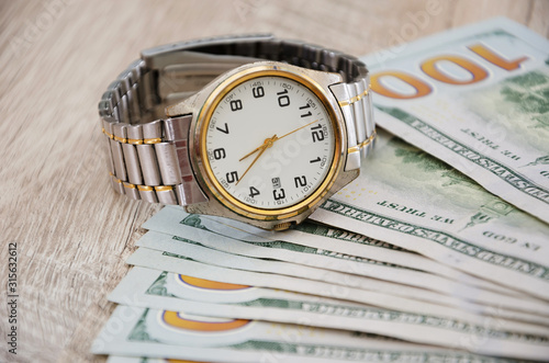 wristwatch and dollars on a wooden table. Close-up.