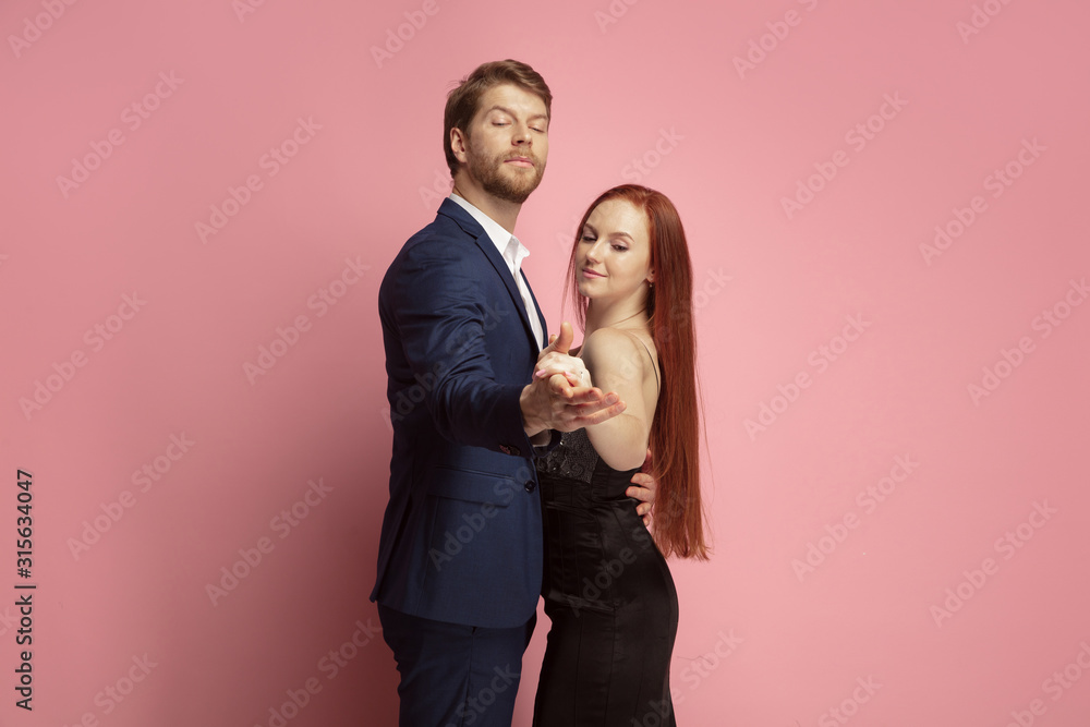 Romantic, passioned dance. Valentine's day celebration, happy caucasian couple isolated on coral studio background. Concept of human emotions, facial expression, love, relations, romantic holidays. Romantic, passioned dance. Valentine's day celebration, happy caucasian couple isolated on coral studio background. Concept of human emotions, facial expression, love, relations, romantic holidays.