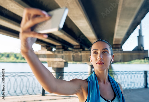 Beautiful sporty woman making selfie during rest between fitness training