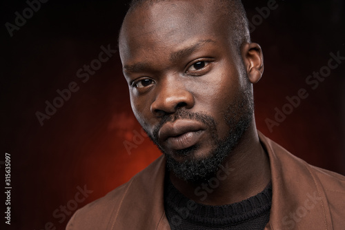 portrait of a black handsome guy on a red background who is looking at the camera