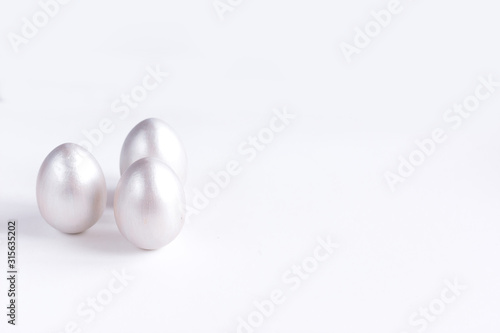 Easter holiday composition. Three eggs of silver color isolated on a white background. Easter flat lay. Copyspace.