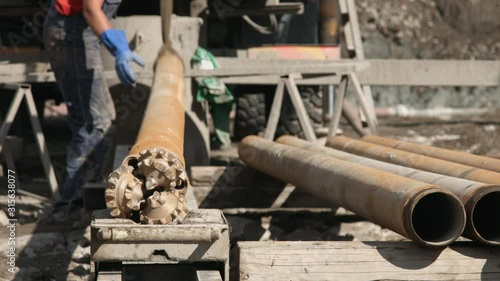 Worker attaching drilling rig pit pipe photo
