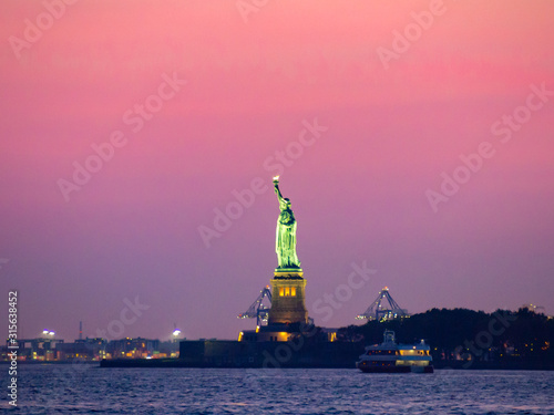 Liberty island, New York City [ Statue of Liberty on Hudson river during cruise sunset at dusk ]