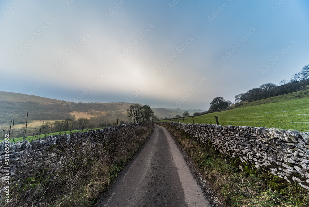 Fototapeta premium Road down the hills through the fields