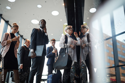 Group of business people with luggage standing in a row and registering at the reception before flight photo