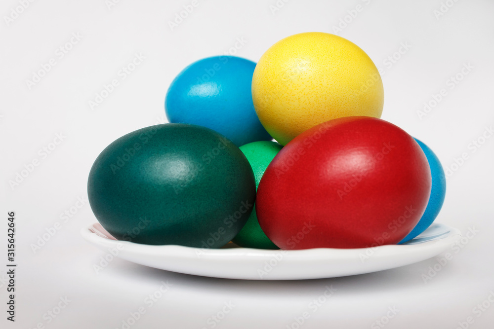 Colored easter eggs in white plate on a background. Isolate. White background. Colored easter eggs in white plate on a background. Isolate. White background.