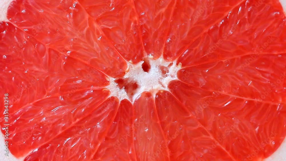 Grapefruit rotates. Cut red fresh citrus fruit juicy spins around its axis. Macro close-up top view. Grapefruit rotates. Cut red fresh citrus fruit juicy spins around its axis. Macro close-up top view.