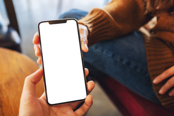 Mockup image of a woman holding and showing white mobile phone with blank black desktop screen to someone