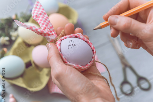 Obraz na płótnie woman makes cute decorative eggs for easter holiday. do-it-yourself easter gifts concept. cute pastel colored eggs w salonie