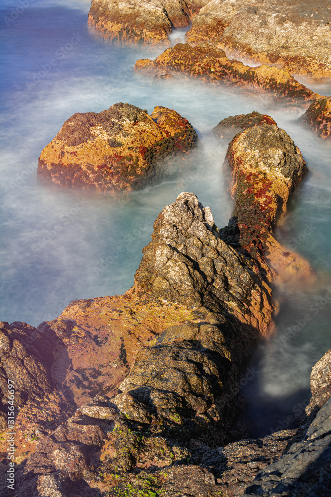 Volcanic rocks in Atlantic ocean, long exposure photography, with afternoon sunlight, Garachico, Tenerife, Canary islands, Spain Volcanic rocks in Atlantic ocean, long exposure photography, with afternoon sunlight, Garachico, Tenerife, Canary islands, Spain