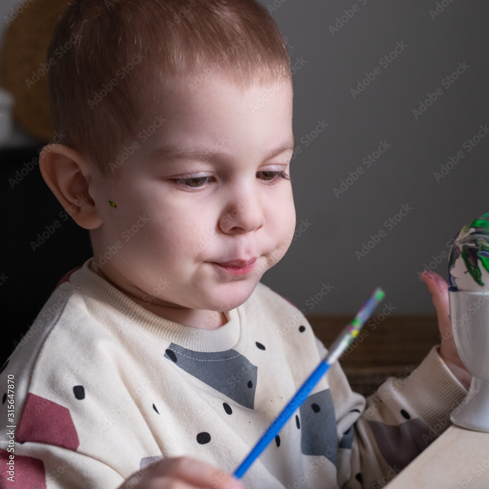 Toddler boy painting easter eggs preparing for holidays. Easter tradition Toddler boy painting easter eggs preparing for holidays. Easter tradition