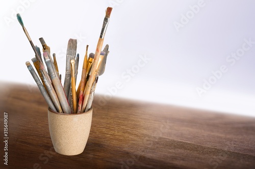 Brushes in a glass jar on the table and white wall