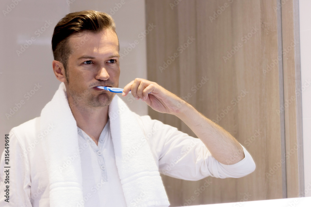 Mid adult man brushing teeth in the bathroom. Mid adult man brushing teeth in the bathroom.