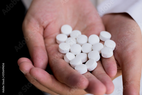 Close-up of man holding pills in hand.