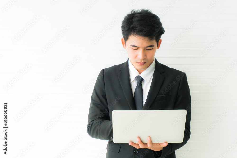 Close up hand of young business man wearing black suit standing and using laptop computer Close up hand of young business man wearing black suit standing and using laptop computer