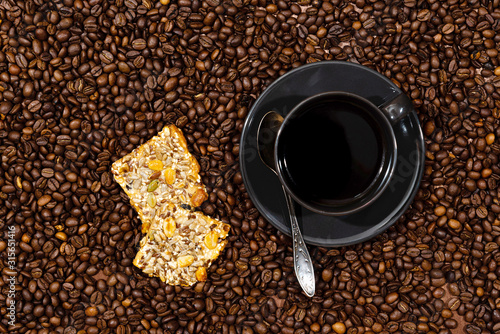 Top view of black coffee mug and cookies on the coffee beans background