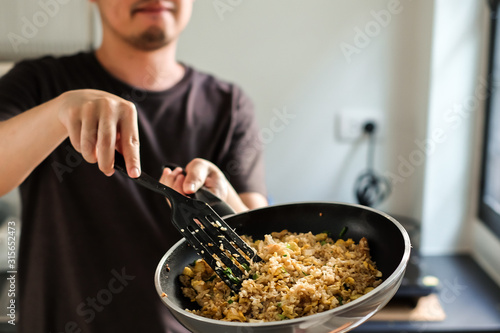 man cooking homemade asian fried rice with eggs in a kitchen