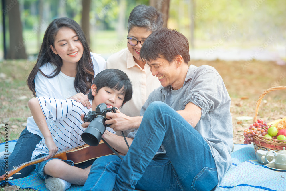 Happy together of asia family have leisure activity in weekend.happy family father use camera show to his son with mother and grandma in background. Happy together of asia family have leisure activity in weekend.happy family father use camera show to his son with mother and grandma in background.
