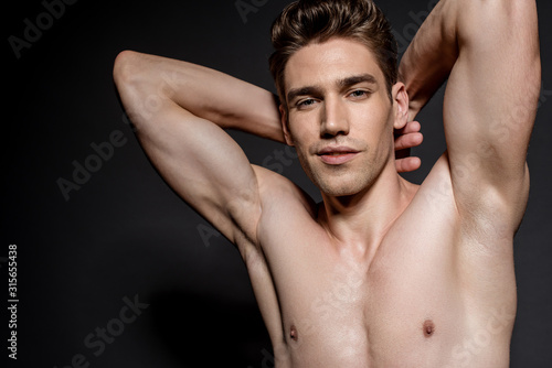 sexy young naked man with muscular torso posing on black background