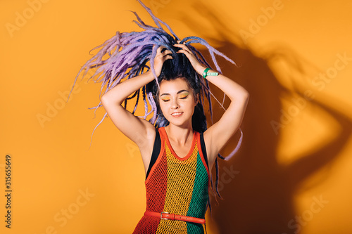 Φωτογραφία Hipster woman wearing in rasta dress and a rasta color make-up is dancing to reggae music
