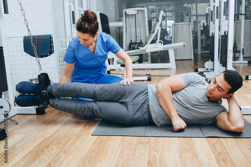 Kinesitherapist training with a male patient of mixed race. The treatment of osteochondritis, joint pain, kinesitherapy exercises photo