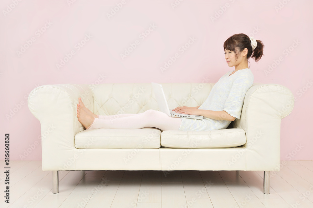 ソファに座ってパソコンを見る若い女性 ソファに座ってパソコンを見る若い女性