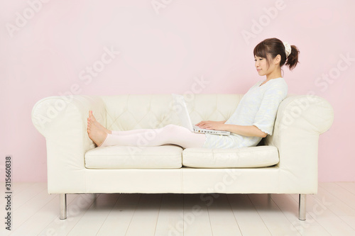 ソファに座ってパソコンを見る若い女性