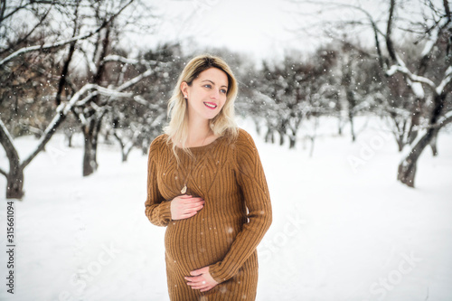 Young happy pregnant woman in snowy forest photo