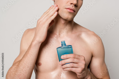 Tableau sur toile cropped view of sexy man with muscular torso applying after shave lotion isolate