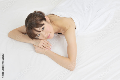 ベッドで横になる若い女性