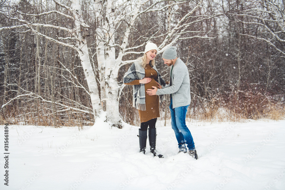 A Pregnant couple together in winter nature