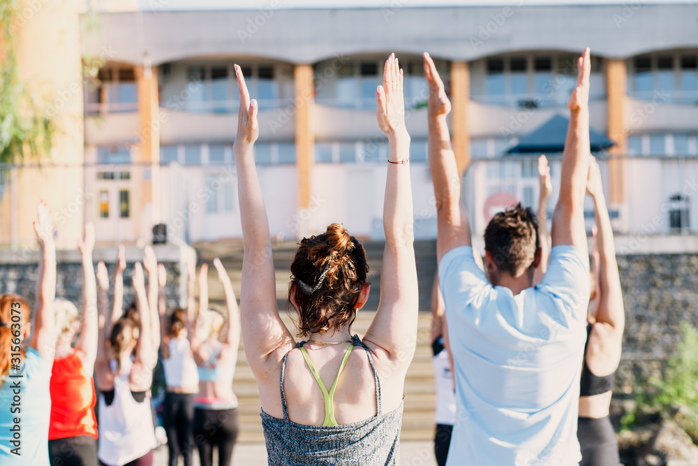 Fototapeta premium A big group of people attending yoga classes on a pontoon near the lake.