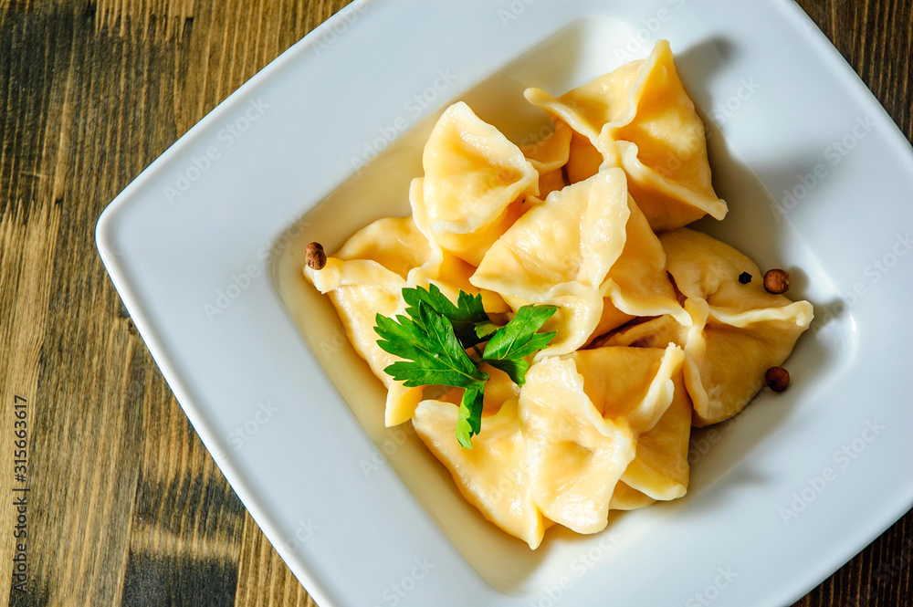 Meat dumplings - russian pelmeni, ravioli with meat on plate on a wooden background Meat dumplings - russian pelmeni, ravioli with meat on plate on a wooden background