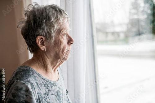 Canvastavla Sad senior woman at home close to window