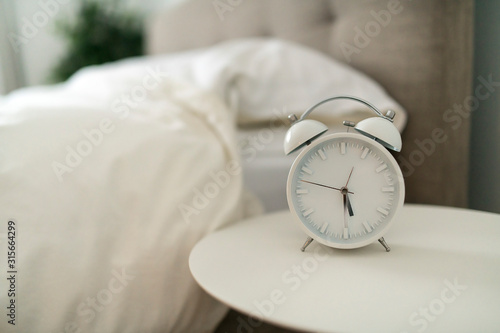 white alarm clock and bed at home