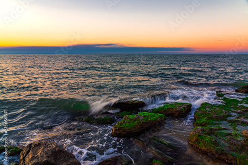 Waves crashing on the rocky seashore at sunset