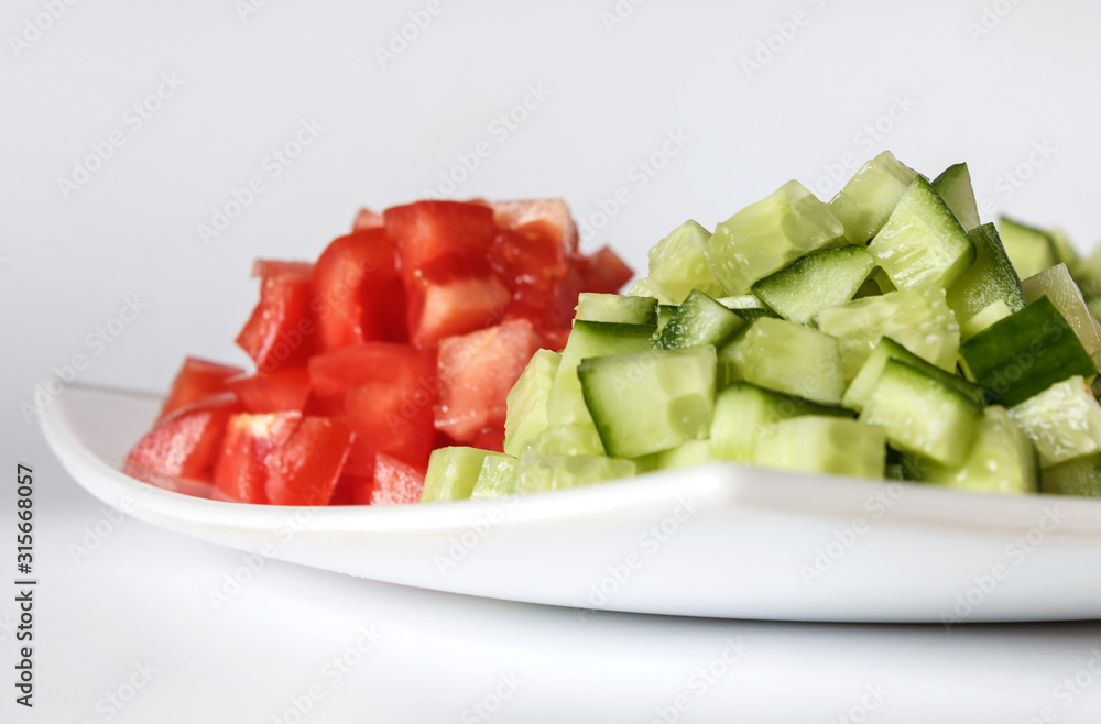 Tomato and cucumber salad on a white plate. Diced raw vegetables. Close-up. Isolate Tomato and cucumber salad on a white plate. Diced raw vegetables. Close-up. Isolate